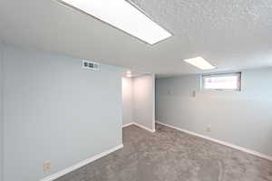 Basement with a textured ceiling and carpet flooring
