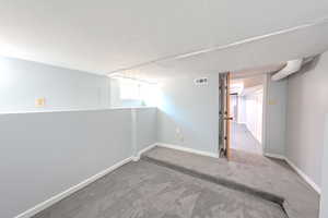 Unfurnished room featuring a textured ceiling and carpet