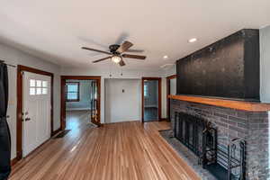 Unfurnished living room featuring a fireplace, wood finished floors, recessed lighting, and a ceiling fan