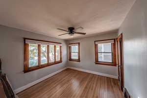 Unfurnished room with light wood-style floors, a ceiling fan, and a textured ceiling