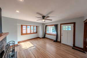 Unfurnished living room featuring a ceiling fan, light wood-type flooring, a fireplace, and recessed lighting