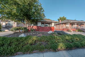 View of property hidden behind natural elements featuring a porch and brick siding