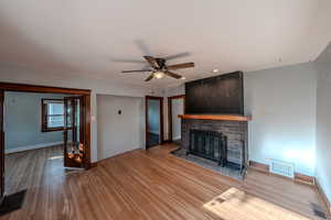 Unfurnished living room with wood finished floors, a ceiling fan, a brick fireplace, and recessed lighting