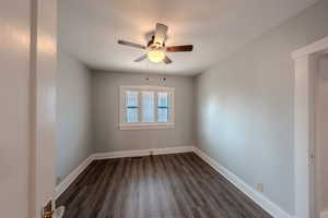 Empty room with a ceiling fan and dark wood-style floors