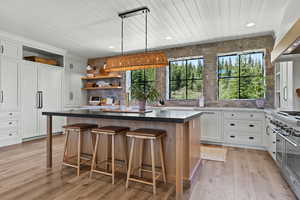Kitchen featuring open shelves, wooden ceiling, a kitchen island, white cabinetry, and a breakfast bar area