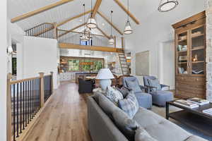 Living area featuring light wood-style flooring, high vaulted ceiling, and a wooden ceiling with exposed beams