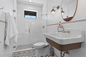 Full bath featuring a stall shower, tile walls, and a wainscoted wall