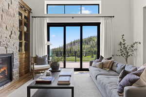 Living area with a stone fireplace, wood finished floors, healthy amount of natural light, a mountain view, and a towering ceiling