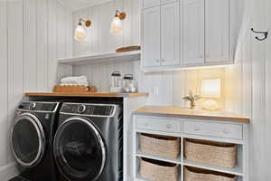 Laundry room with independent washer and dryer, cabinet space, and a decorative wall