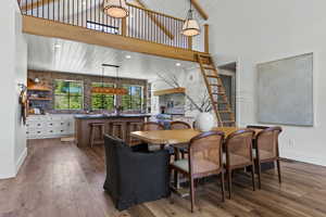 Dining room with wood-type flooring, a high ceiling, and recessed lighting