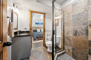 Ensuite bathroom with vanity, stone finish flooring, and a shower stall