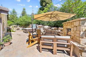 View of patio / terrace with a hot tub and an outdoor living space with a fireplace