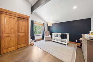 Bedroom with wood finished floors, recessed lighting, and a crib