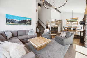 Living area with a chandelier, stairs, wood finished floors, and high vaulted ceiling