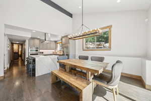 Dining area featuring dark wood-type flooring, a chandelier, recessed lighting, high vaulted ceiling, and beamed ceiling