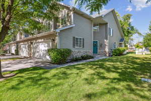 View of front facade featuring concrete driveway, an attached garage, a front yard, and stone siding
