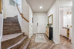 Foyer featuring light wood finished floors, stairway, and recessed lighting