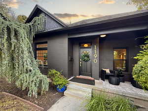 Doorway to property featuring brick siding and covered porch