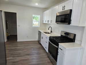 Kitchen featuring stainless steel appliances, dark wood-type flooring, white cabinetry, a textured ceiling, and recessed lighting