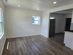 Unfurnished room featuring a textured ceiling, dark wood finished floors, and recessed lighting