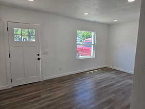 Entryway with plenty of natural light, a textured ceiling, dark wood finished floors, and recessed lighting