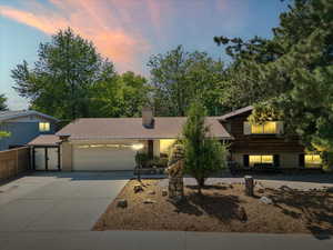 Tri-level home with an attached garage, driveway, a chimney, and brick siding