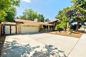 Split level home with an attached garage, driveway, and a chimney