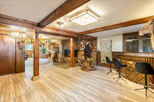 Basement featuring wood finished floors, a wainscoted wall, wooden walls, and a glass covered fireplace