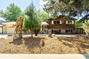 Tri-level home featuring an attached garage, concrete driveway, and brick siding