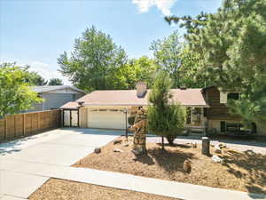 Tri-level home featuring a garage, concrete driveway, and a chimney