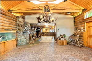 Dining room with a wood ceiling with exposed beams, a chandelier, log walls, and stone finish flooring