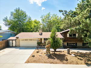 Tri-level home with an attached garage, concrete driveway, a chimney, and brick siding