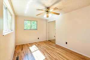 Unfurnished room featuring light wood-type flooring, ceiling fan, and a textured ceiling