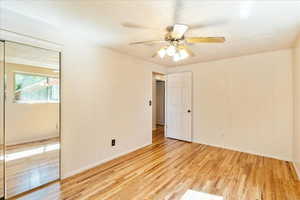 Spare room featuring light wood-style floors, a ceiling fan, and a textured ceiling