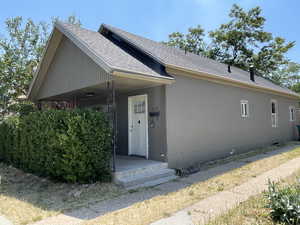 Ranch-style home featuring roof with shingles and stucco siding