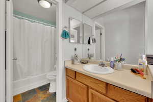 Full bathroom with stone finish flooring, vanity, and shower / bath combination with curtain