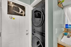 Washroom featuring estacked washer and dryer and a sink