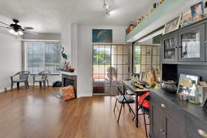 Home office featuring a textured ceiling, wood finished floors, a ceiling fan, and a tiled fireplace