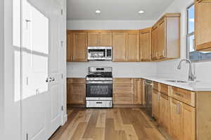 Kitchen featuring appliances with stainless steel finishes, light wood-style flooring, light countertops, recessed lighting, and brown cabinets
