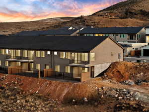 Back of house at dusk featuring a balcony, stucco siding, a mountain view, and a residential view