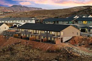 Back of house featuring a residential view, stucco siding, a mountain view, and a balcony