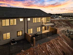 Rear view of house with a balcony, stucco siding, and a patio area