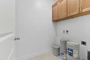 Laundry area with hookup for an electric dryer, cabinet space, washer hookup, and tile patterned floors