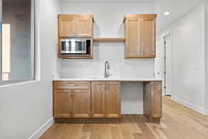 Kitchen featuring stainless steel microwave, open shelves, light wood-style floors, light countertops, and recessed lighting