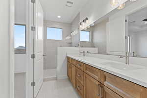 Bathroom featuring double vanity, walk in shower, and tile patterned floors