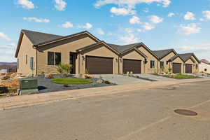 Single story home featuring an attached garage, stucco siding, concrete driveway, and stone siding