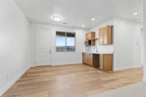 Kitchen with stainless steel microwave, light wood-type flooring, light countertops, and recessed lighting