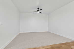 Empty room featuring ceiling fan and light carpet