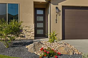 Property entrance featuring stucco siding, a garage, and concrete driveway