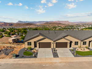 Ranch-style house featuring stucco siding, stone siding, a mountain view, and an attached garage